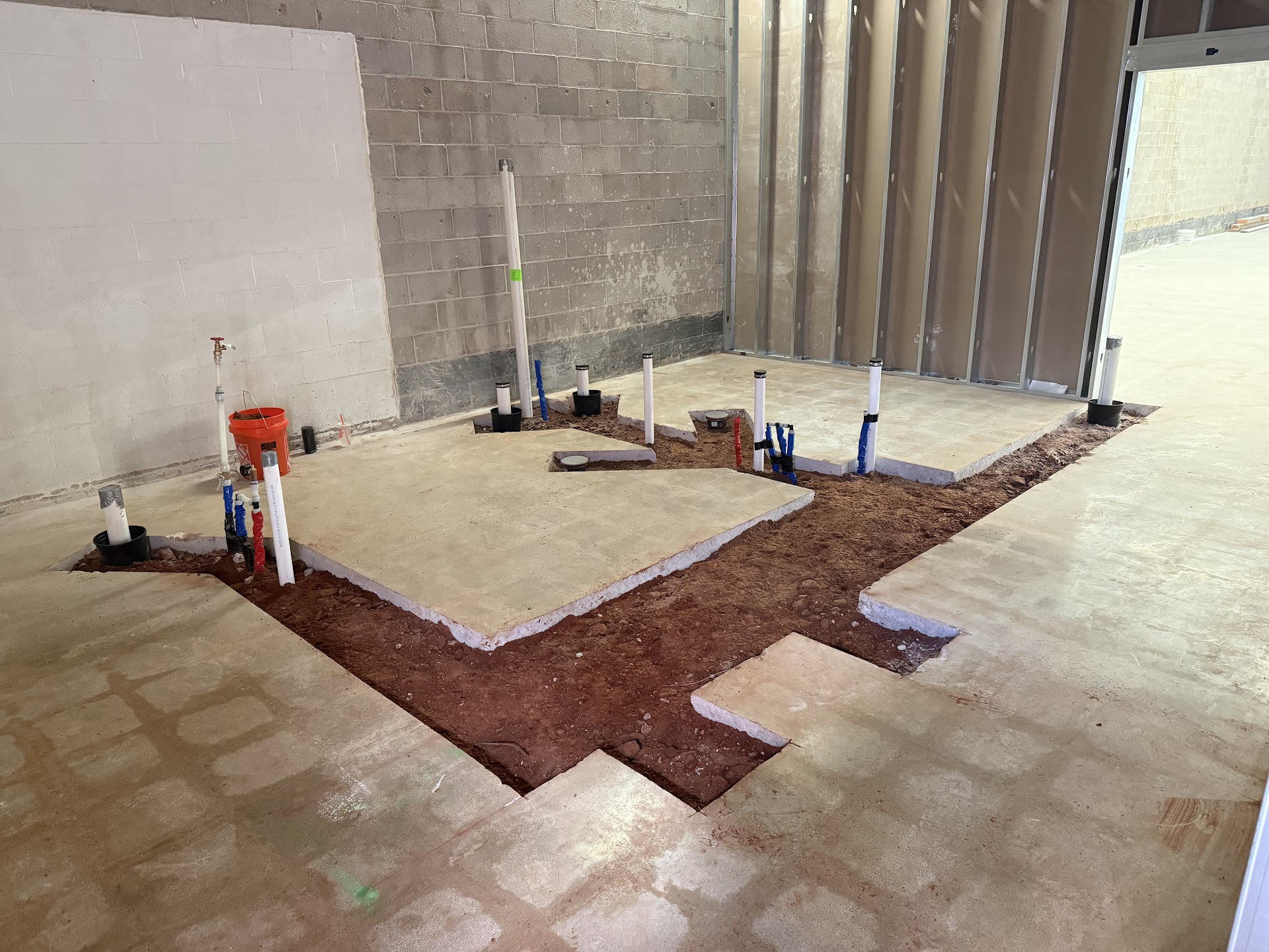 Interior plumbing rough-in set through a commercial concrete floor.