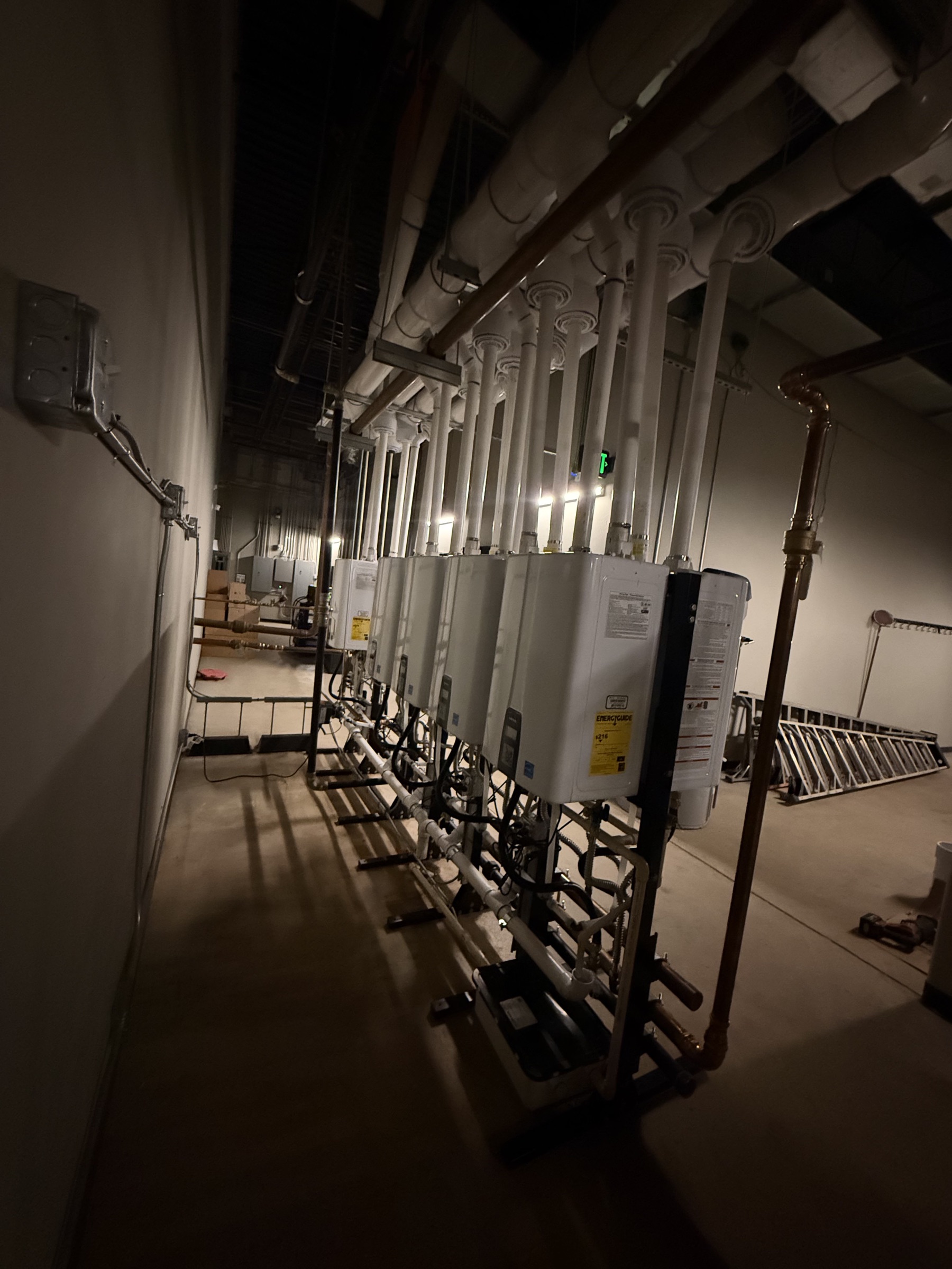 Long view along multiple installed tankless water heaters and connected piping.