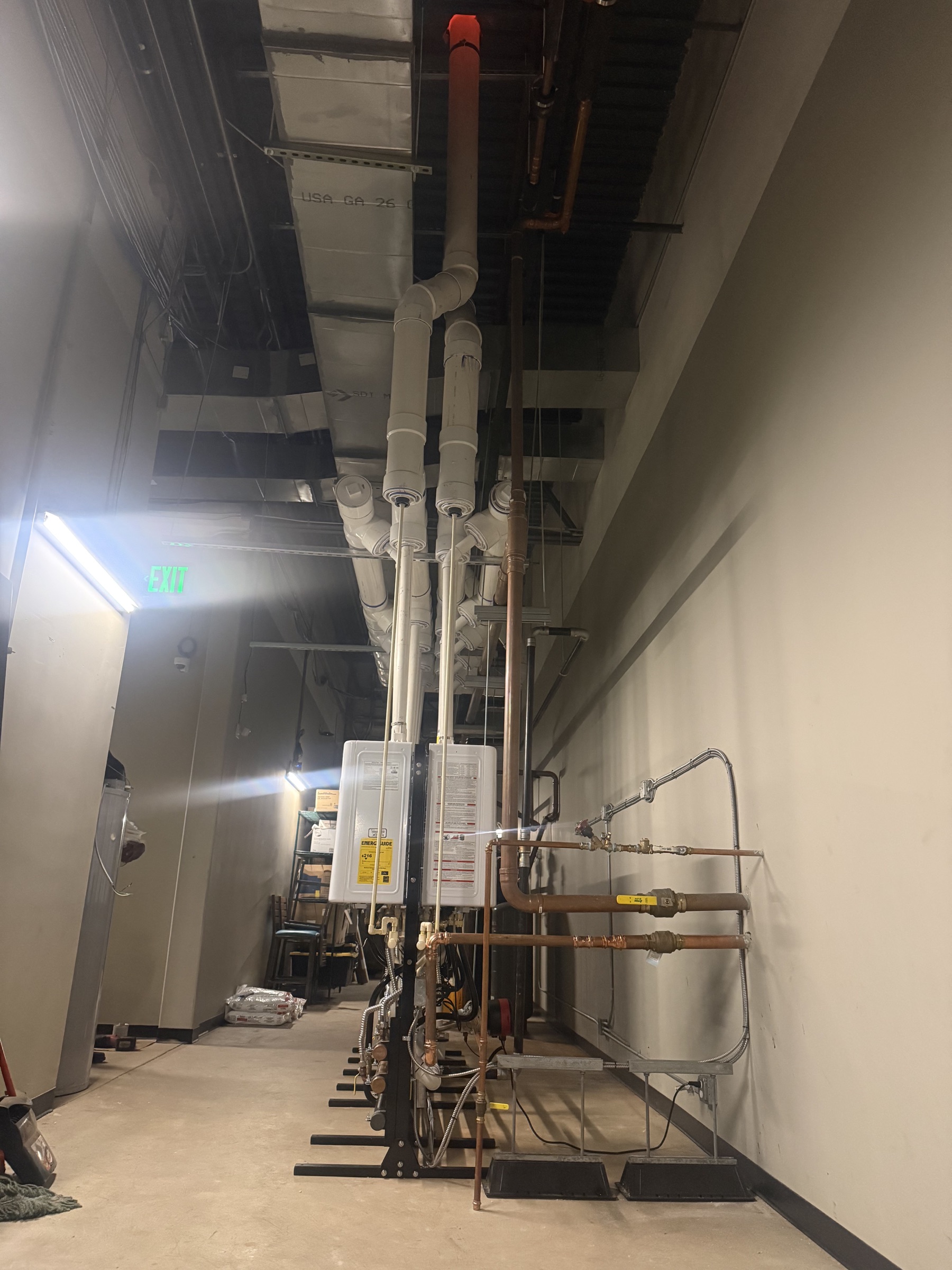 Side view of installed tankless water-heater equipment, copper piping, and venting.