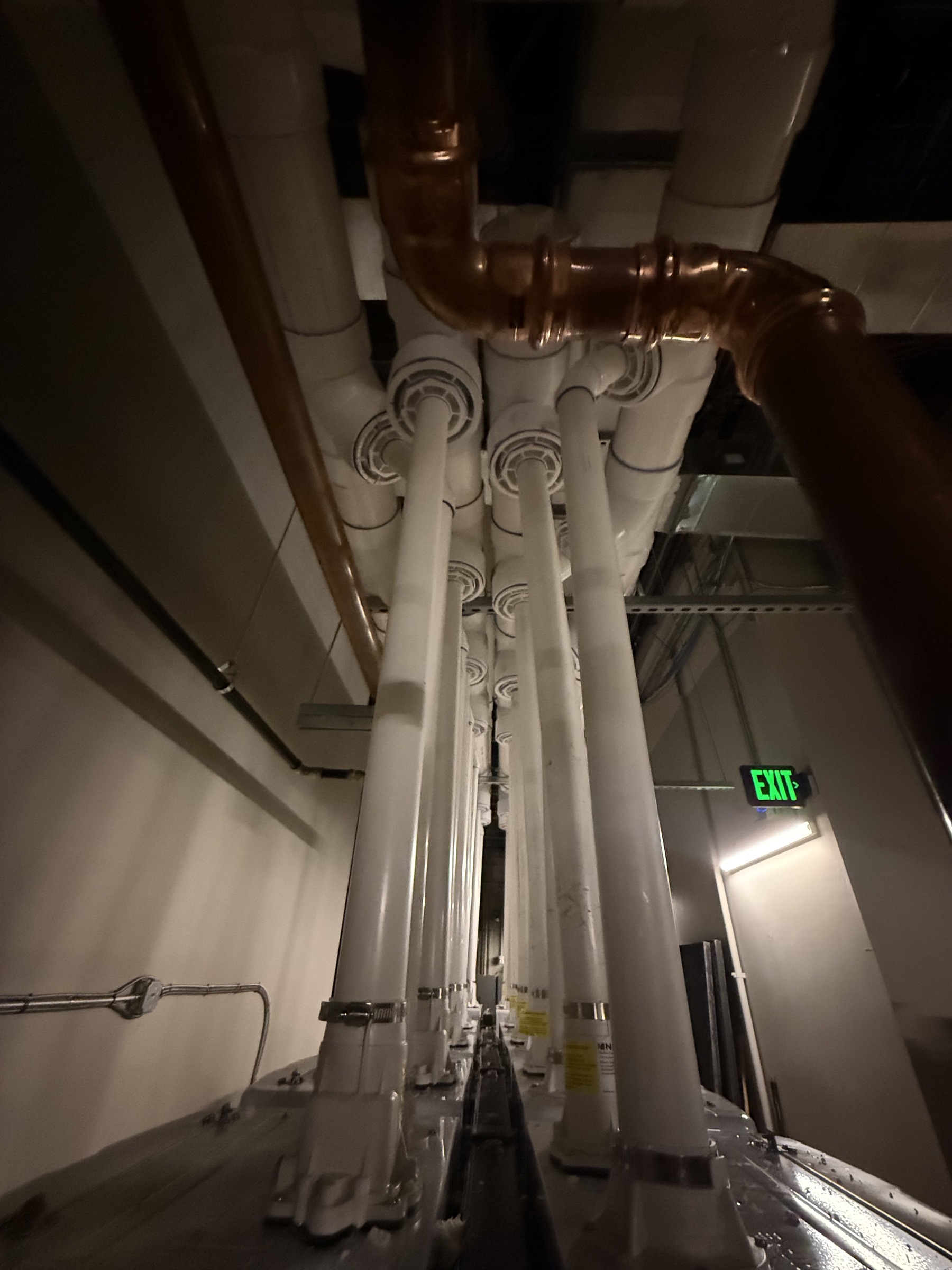 Overhead vent runs and copper piping connected to multiple tankless water heaters.