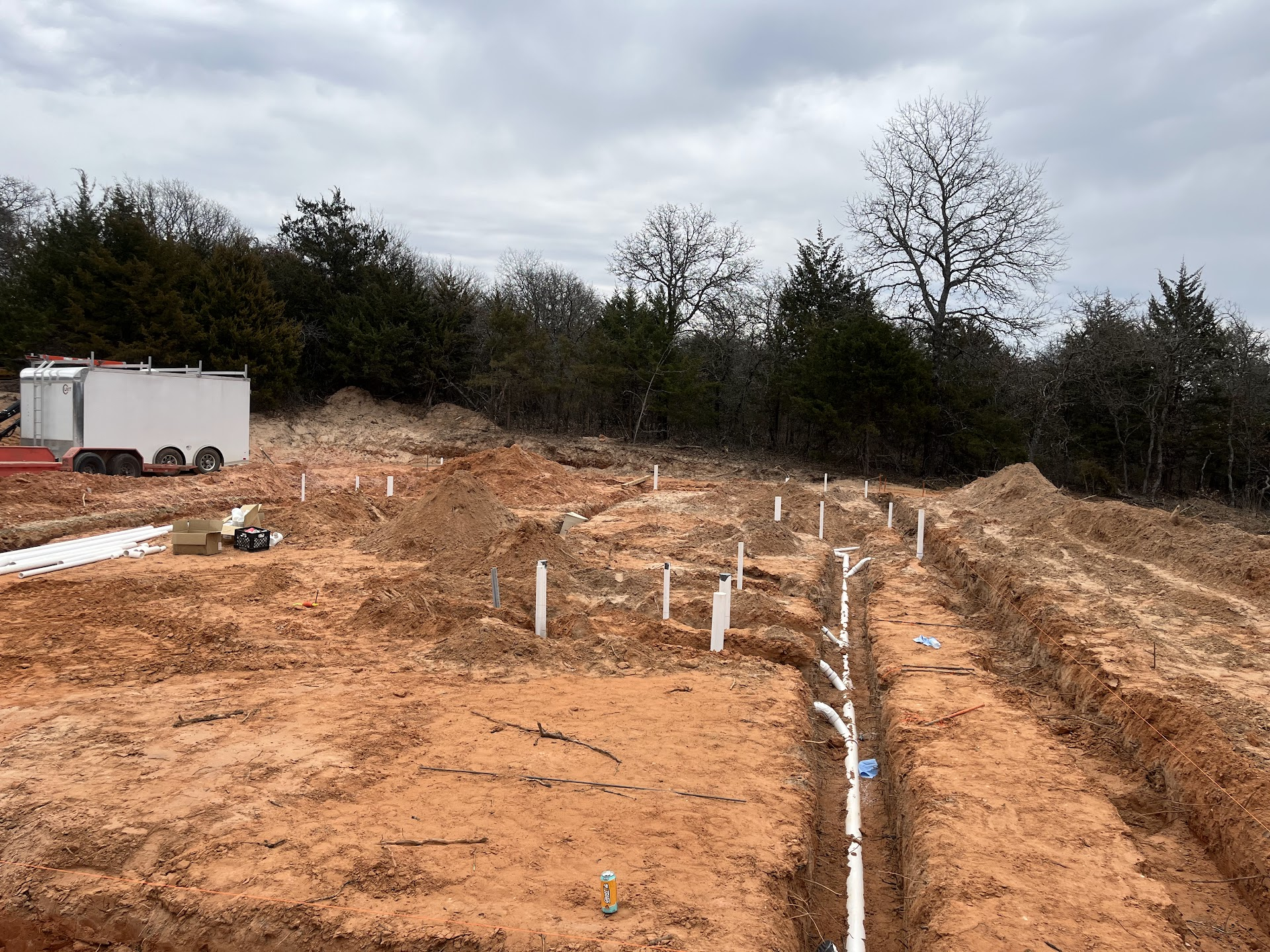 Underground plumbing lines installed across a broad new-construction site.