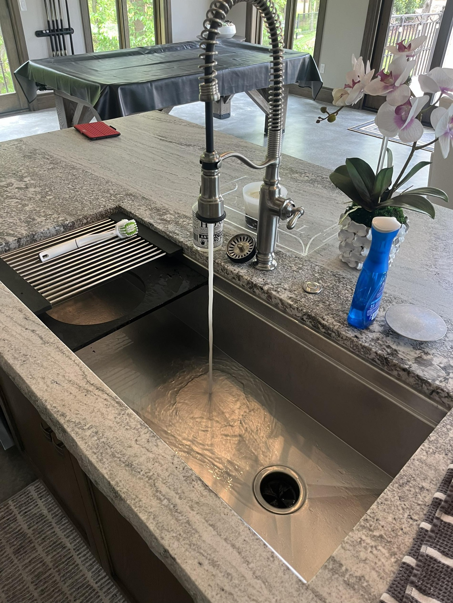 Kitchen sink with a high-arc faucet running into a stainless-steel basin.
