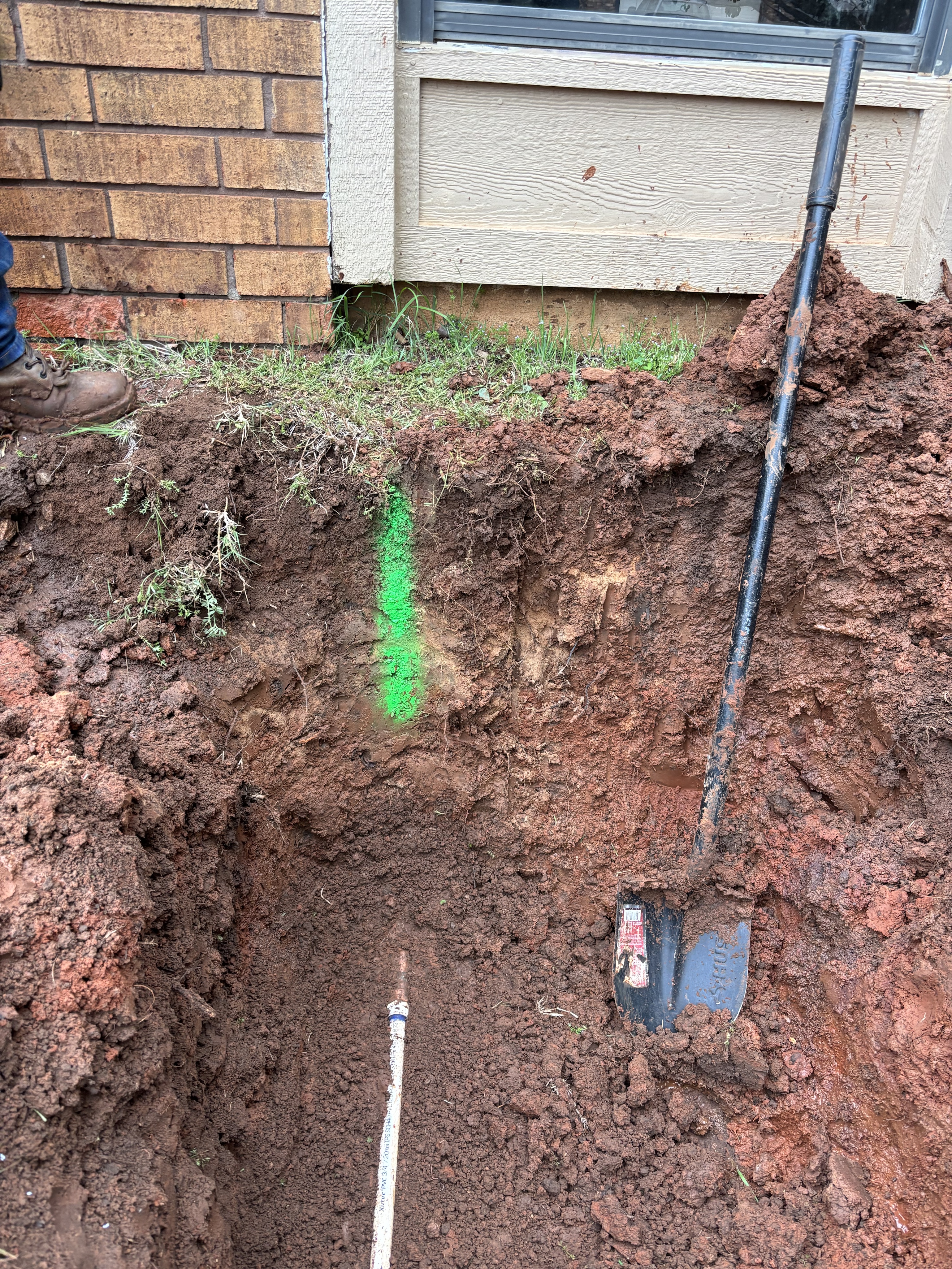 Open service-line trench extending across a residential yard.
