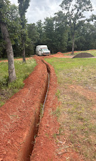 Long yard trench prepared for plumbing service line work.
